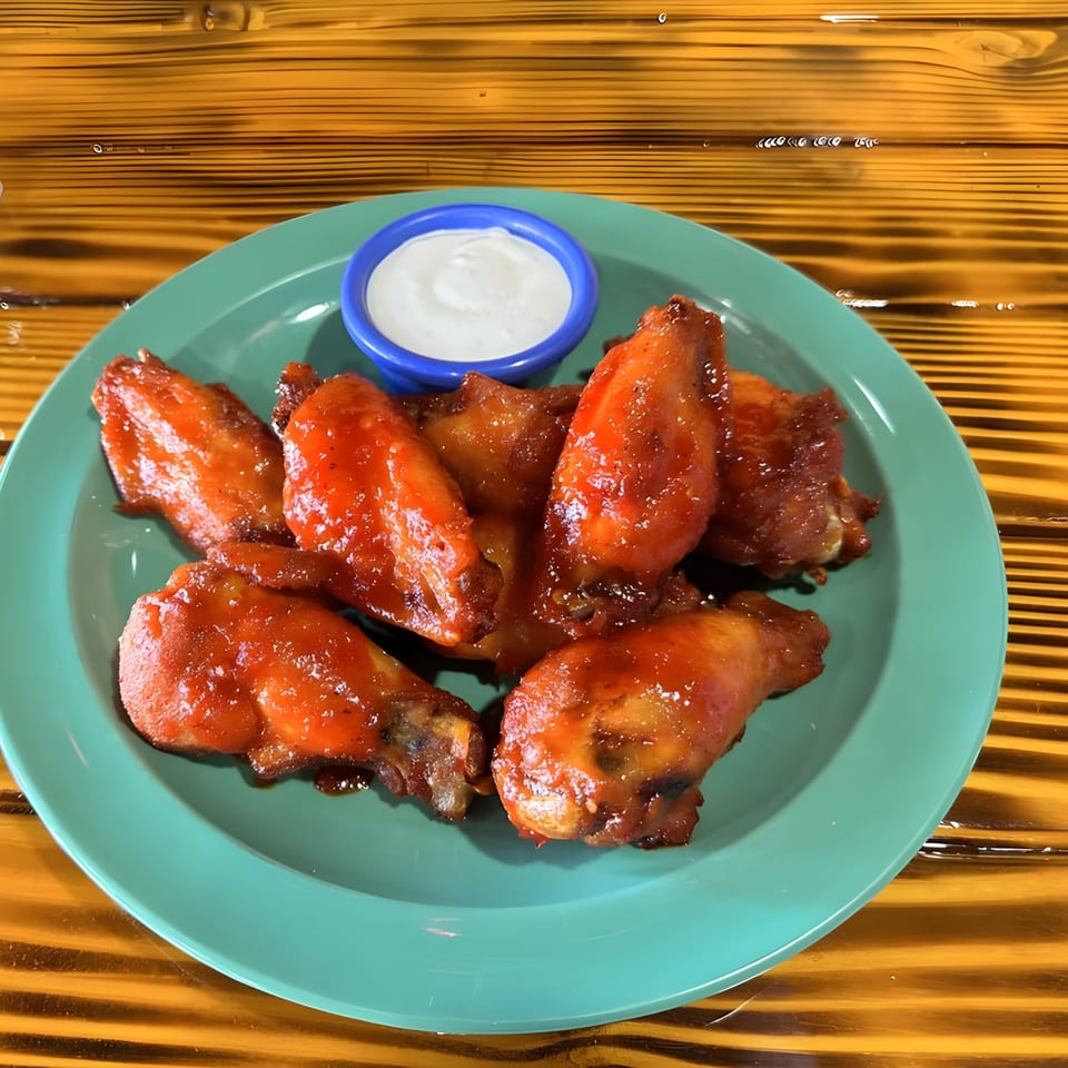 El Agave Mexican Cuisine's spicy chicken wings with a side of ranch dressing on a teal plate.